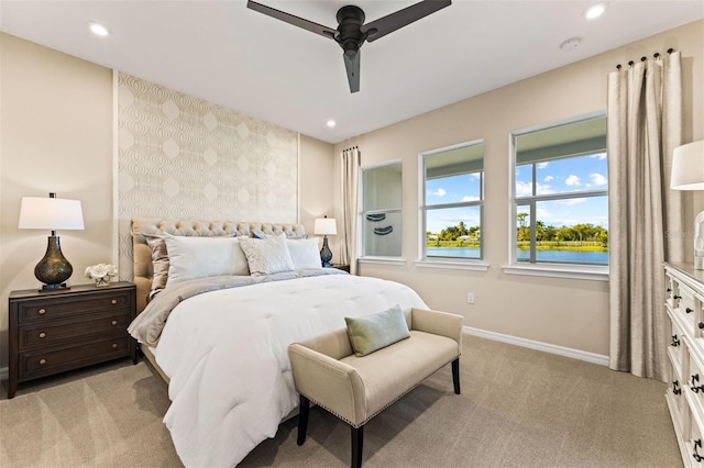 bedroom with ceiling fan, a water view, and light colored carpet