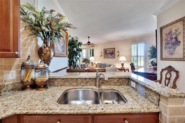 kitchen featuring light stone countertops, sink, ceiling fan, a textured ceiling, and ornamental molding