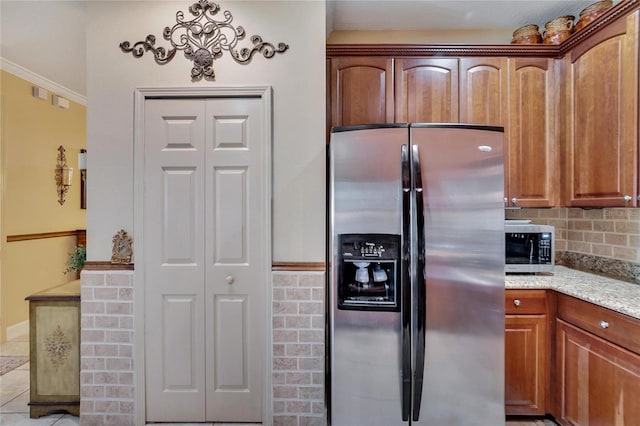 kitchen featuring crown molding, decorative backsplash, appliances with stainless steel finishes, light tile patterned flooring, and light stone counters