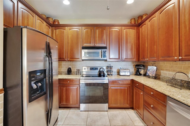 kitchen featuring appliances with stainless steel finishes, light tile patterned floors, tasteful backsplash, and light stone counters