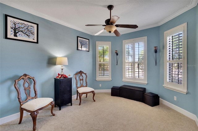 sitting room with ceiling fan, crown molding, and carpet