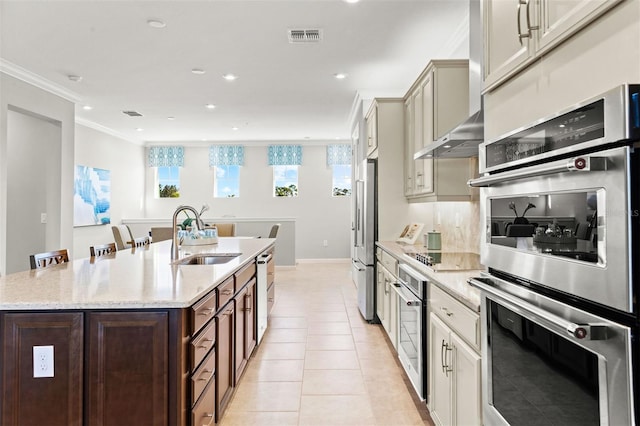 kitchen with light stone countertops, sink, stainless steel appliances, cream cabinetry, and light tile patterned floors