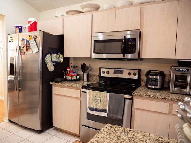 kitchen with light stone counters, light brown cabinetry, light tile patterned floors, and stainless steel appliances