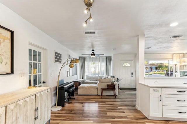 living room featuring ceiling fan, dark wood-type flooring, and a wealth of natural light