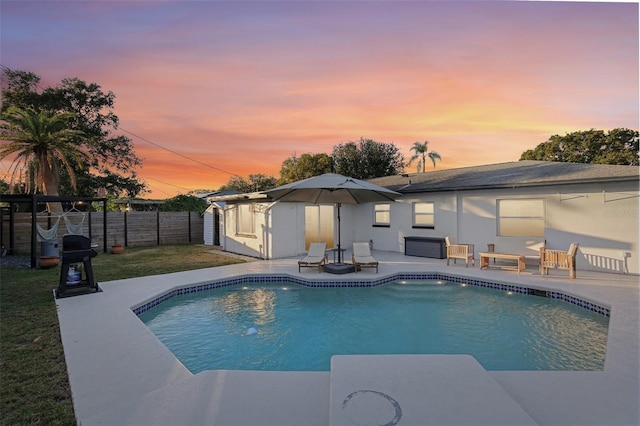 pool at dusk with a yard and a patio