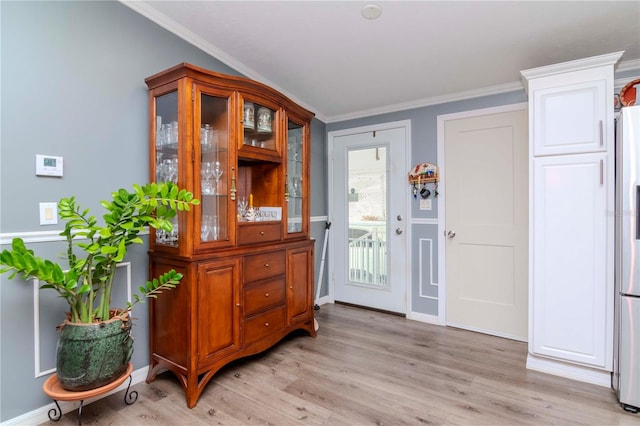 entryway with light hardwood / wood-style floors and crown molding