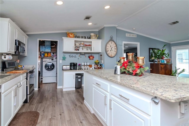 kitchen featuring a center island, vaulted ceiling, washer and clothes dryer, white cabinets, and appliances with stainless steel finishes