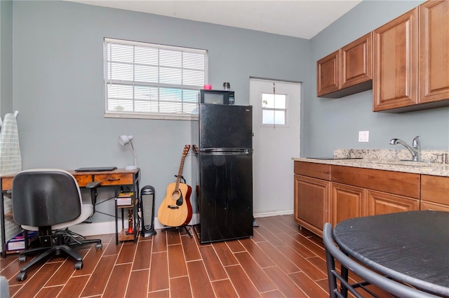 kitchen featuring black refrigerator, plenty of natural light, dark wood-type flooring, and sink