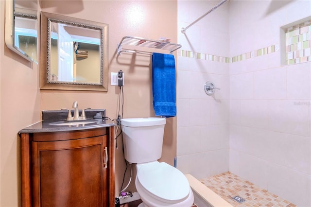 bathroom with vanity, toilet, and a tile shower