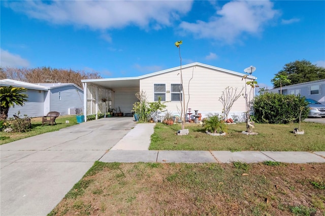 manufactured / mobile home featuring a front lawn and a carport