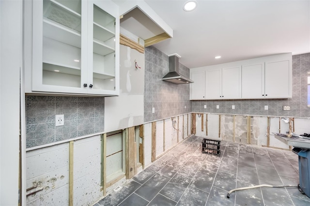 kitchen with wall chimney exhaust hood, white cabinetry, and tasteful backsplash