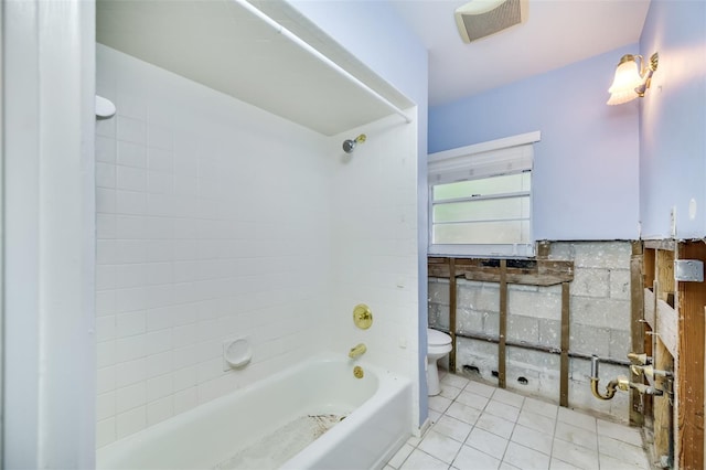 bathroom featuring tile patterned flooring, tiled shower / bath combo, and toilet