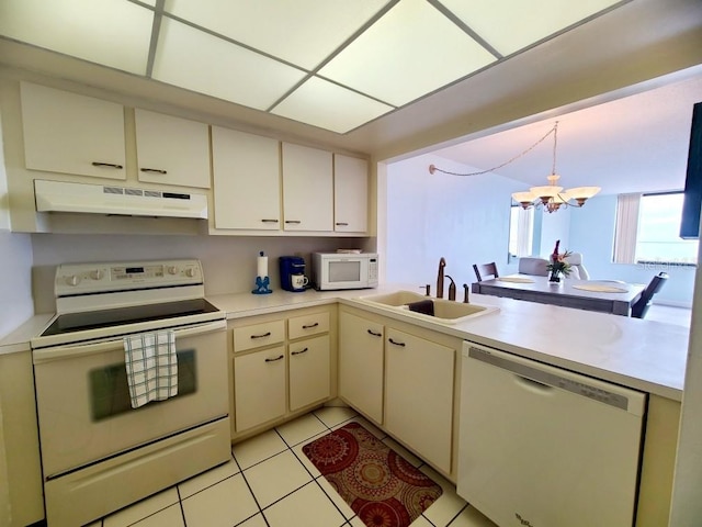 kitchen with sink, white appliances, light tile patterned floors, a chandelier, and cream cabinets