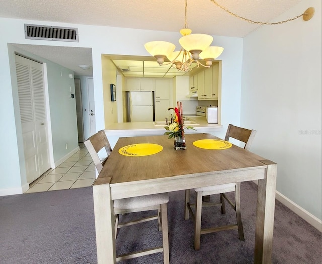 unfurnished dining area featuring sink, a notable chandelier, light tile patterned flooring, and a textured ceiling