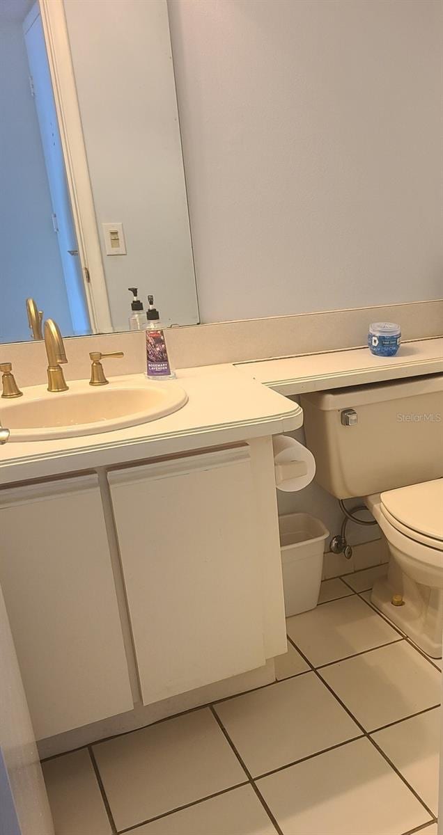 bathroom with toilet, vanity, and tile patterned flooring