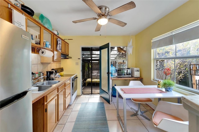 kitchen featuring sink, decorative backsplash, ceiling fan, light tile patterned floors, and appliances with stainless steel finishes