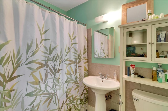 bathroom featuring curtained shower, tile walls, and toilet