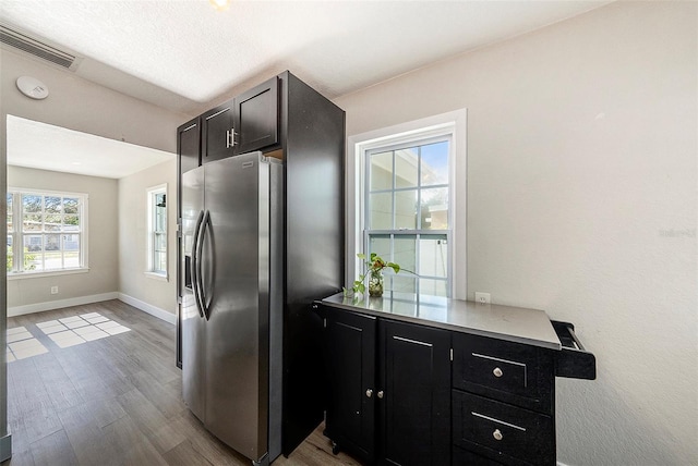 kitchen with stainless steel fridge, light hardwood / wood-style flooring, and a textured ceiling