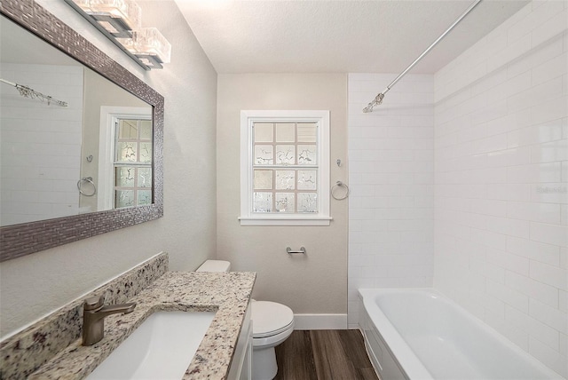 full bathroom featuring tiled shower / bath combo, a textured ceiling, toilet, vanity, and hardwood / wood-style flooring