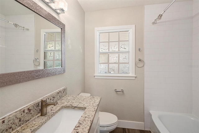 full bathroom with vanity, wood-type flooring, tiled shower / bath combo, and toilet