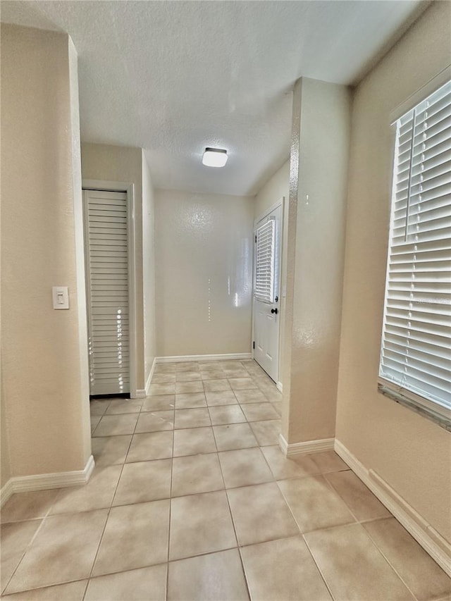 hall with light tile patterned floors and a textured ceiling