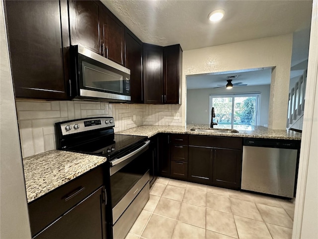 kitchen with a sink, light stone counters, tasteful backsplash, and appliances with stainless steel finishes