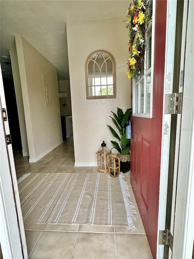 entryway with tile patterned flooring, baseboards, and a textured wall