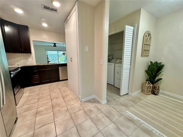 kitchen with baseboards, visible vents, stainless steel appliances, washer and dryer, and backsplash