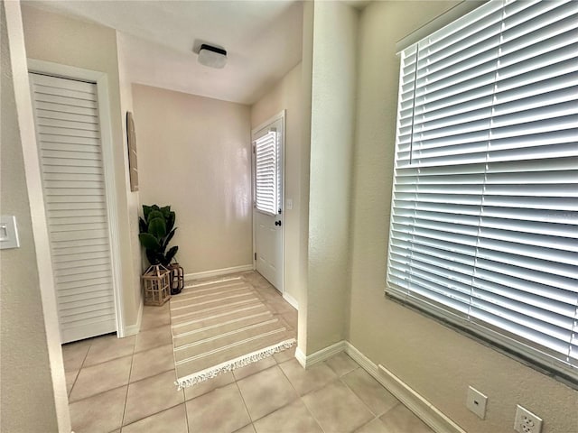 corridor featuring light tile patterned floors and baseboards