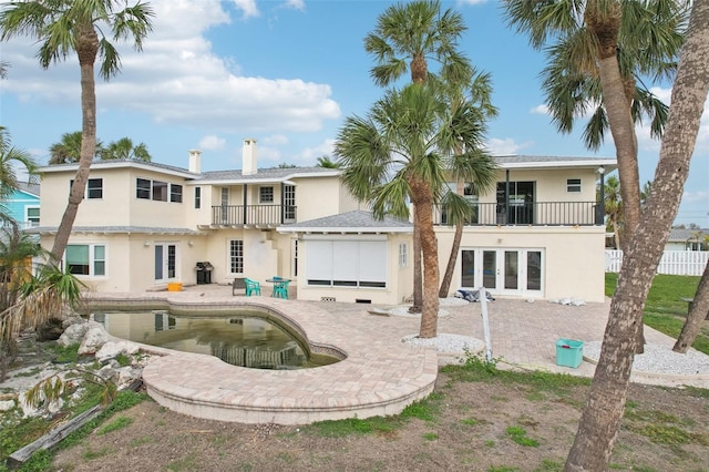 back of property featuring a balcony, a patio, and french doors