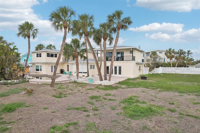 rear view of property with french doors, a balcony, a patio area, and a lawn