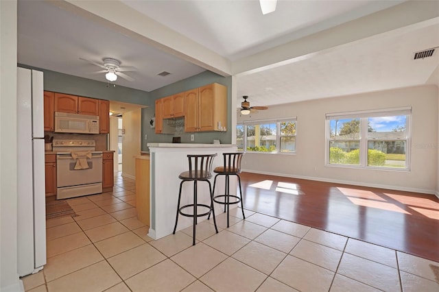 kitchen with beamed ceiling, light tile patterned flooring, and white appliances