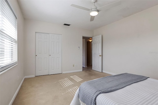 bedroom with ceiling fan, a closet, and light colored carpet