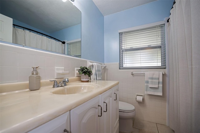 bathroom featuring tile patterned flooring, vanity, toilet, and tile walls