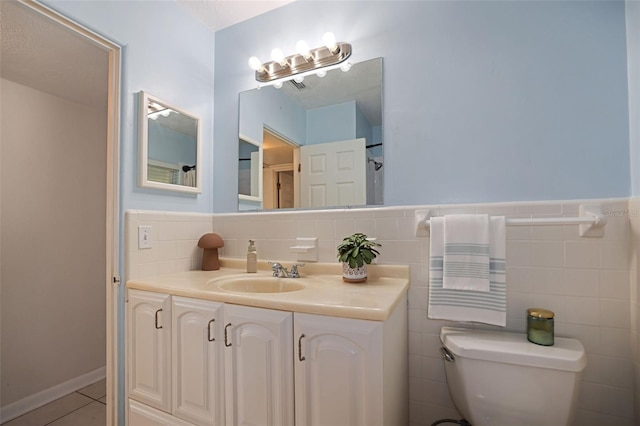 bathroom with tile patterned flooring, vanity, toilet, and tile walls