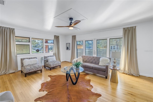 living room with ceiling fan, light wood-type flooring, ornamental molding, and a wealth of natural light