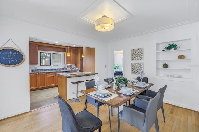 dining area with built in features, crown molding, and light hardwood / wood-style flooring