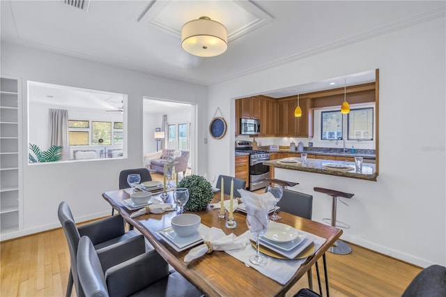 dining room featuring ceiling fan, light wood-type flooring, and sink