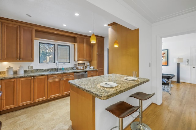 kitchen featuring light stone countertops, sink, hanging light fixtures, a breakfast bar, and light wood-type flooring