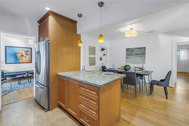 kitchen featuring built in shelves, light stone countertops, hanging light fixtures, stainless steel fridge, and light hardwood / wood-style floors