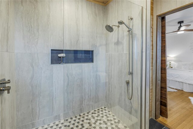 bathroom with a tile shower and ceiling fan