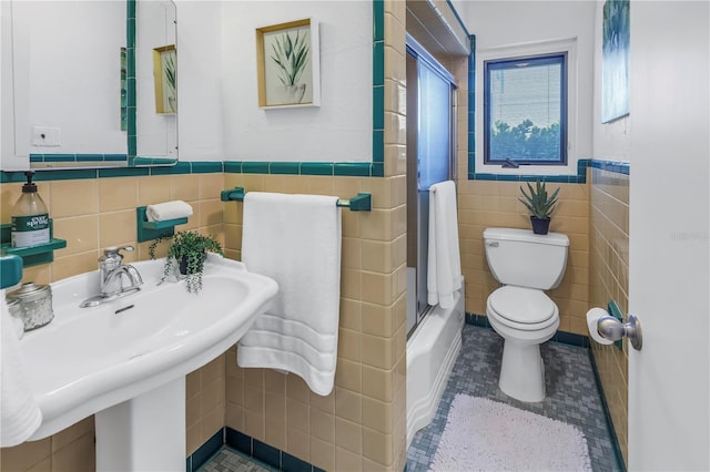 bathroom with tile patterned floors, toilet, a shower with shower door, and tile walls