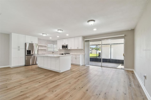 kitchen with decorative backsplash, light wood-type flooring, stainless steel appliances, and white cabinetry