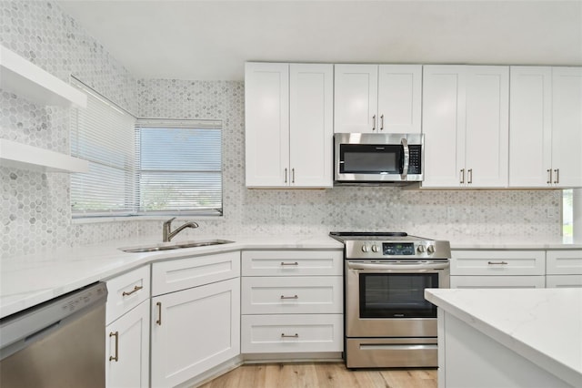 kitchen featuring sink, light hardwood / wood-style flooring, light stone countertops, white cabinetry, and stainless steel appliances