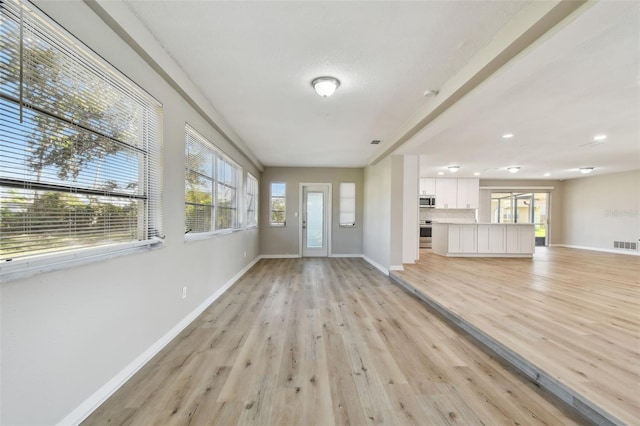 unfurnished living room featuring light wood-type flooring and a healthy amount of sunlight