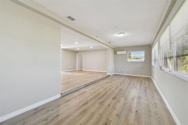 empty room with light hardwood / wood-style flooring and a wall unit AC