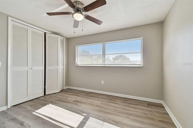 unfurnished bedroom with a textured ceiling, light wood-type flooring, a closet, and ceiling fan