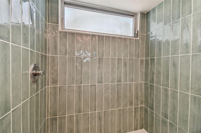 bathroom with a tile shower and a textured ceiling