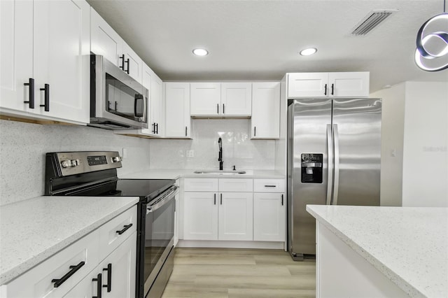 kitchen with light stone countertops, sink, light wood-type flooring, and appliances with stainless steel finishes