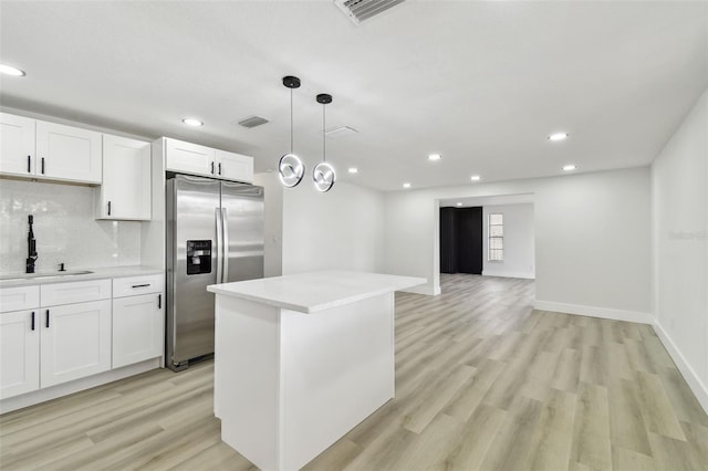 kitchen featuring stainless steel fridge, white cabinetry, sink, and light hardwood / wood-style flooring